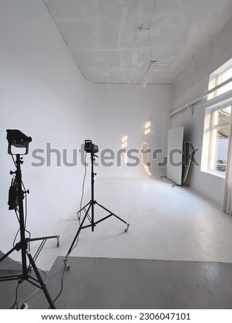 A white cyclorama in a photo studio, on the right is a window through which sunlight falls on the photo frame, which leaves two light shadows. To the left of the frame, there are two sources of studio