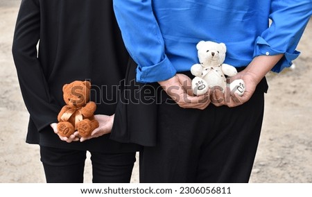 teddy bear. A Man and A woman hold a teddy bear in hand at dawn in the sand.