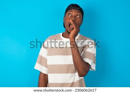young man wearing striped T-shirt over blue studio background hear incredible private news impressed scream share Royalty-Free Stock Photo #2306062617