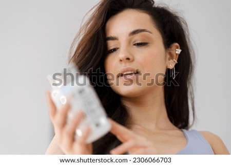 Closeup portrait of beautiful woman holding protein supplement bottle standing in kitchen. Positive emotions, healthy lifestyle concept  Royalty-Free Stock Photo #2306066703