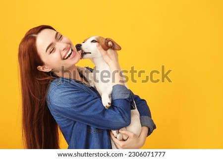 Happy woman with her cute Jack Russell Terrier dog on orange background. Space for text Royalty-Free Stock Photo #2306071777