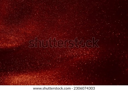 Glittering flows of gold particles in red fluid. Various stains and overflows of gold particles in liquid with burgundy tints. Abstract shimmering background.