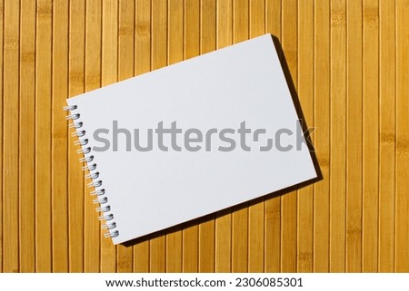 Open sketchbook with blank white page and spiral on a bamboo background Mock up for your design or text Sketch book perfectly Page top is pure white Top view Great template for drawing hand lettering
