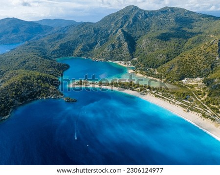 Ultrawide drone image of the serene Ölüdeniz Beach, Fethiye, Muğla. The picture paints a scene of tranquility with its pristine beach and clear blue waters.