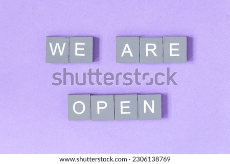 We are open quote, welcome sign for business or caffe, wooden letters on violet background