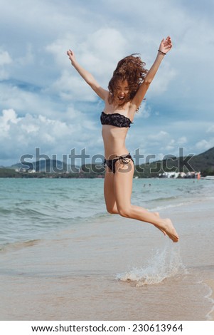 beautiful fun girl jumping on the beach near the sea