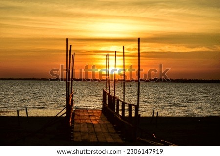 A wooden bridge that extends into the water in front of Saen Tor Beach, Sirindhorn Dam Ubon Ratchathani Province,Thailand,new landmark on the border of neighboring countries, Laos.During the sunset  Royalty-Free Stock Photo #2306147919