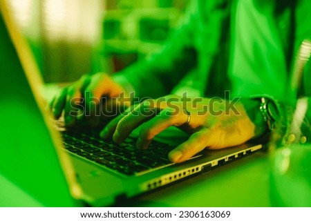 Cropped picture of a senior full-stack developer typing on a keyboard in his green-lighted home office. Hands typing code and programming on a laptop from home.