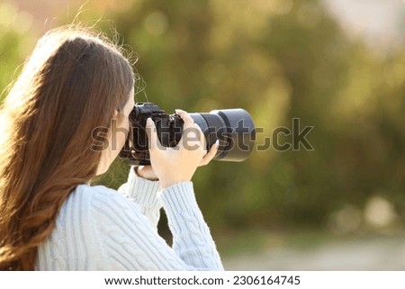 Back view portrait of a photographer taking photos with mirrorless camera in a park Royalty-Free Stock Photo #2306164745