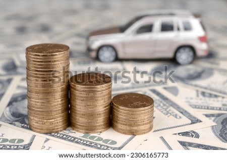 Toy car model at the stacks of golden coins lies on many dollar bills, fixed rate for car loan or saving money for buy car, trade with cash, finance concept