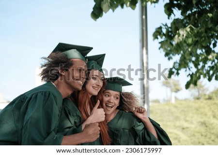 Three friends taking a photo celebrating their university graduation with the border suit. Concept: graduation, university, studies