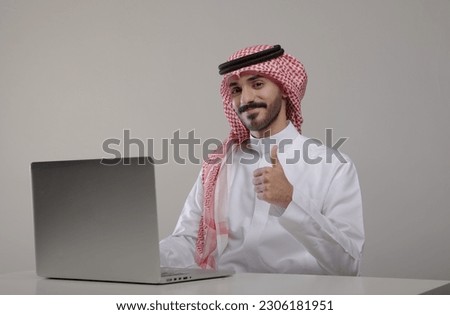 A saudi character sites at the desk using laptop with different positions on withe background Royalty-Free Stock Photo #2306181951