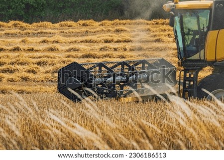 Close up of cab and cutter bar of combine harvester mowing wheat field