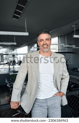 Happy proud stylish mid aged mature professional business man ceo, successful confident smiling good looking male executive wearing suit standing in office looking at camera, vertical portrait.