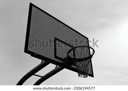A basketball hoop, mounted on a backboard, providing a target for players to shoot the ball through, adding excitement and challenge to the game. Royalty-Free Stock Photo #2306194577