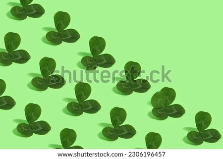 
Green three leaf clover pattern on a green background with one four leaf clover.