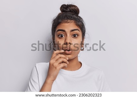 Indoor studio portrait of stunned speechless Indian female model stands amazed has shocked facial expression dressed in casual t shirt isolated over white background. Human face expressions. Royalty-Free Stock Photo #2306202323