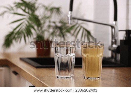 House water filtration system to drinkable condition. Glass of clear water after reverse osmos filtration and glass of dirty water on tabletop on kitchen. Evidence of contamination of tap water. Royalty-Free Stock Photo #2306202401