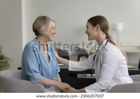 Female doctor tells positive prognosis to aged woman patient, holds her hands, touches shoulder, provides support and medical care in hospital, take care of aged patient in private clinic. Healthcare Royalty-Free Stock Photo #2306207037