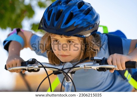 Boy in a helmet riding bike. Boy in safety helmet riding bike in city park. Child first bike. Kid outdoors summer activities. Kid on bicycle. Little child riding bike in summer park on a driveway.