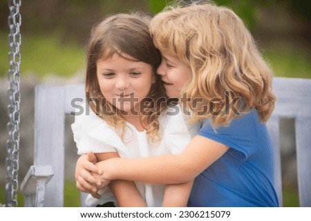 Little boy and girl best friends hugging. Kids kissing each other with love at summer park. Happy children having fun outdoors. Little girl kissing little boy outdoors in park. Shy girl.