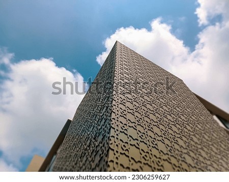 Low angle photography of islamic pattern wall details of high-rise buildings. Architectural Exterior Against Blue Sky with White Clouds.