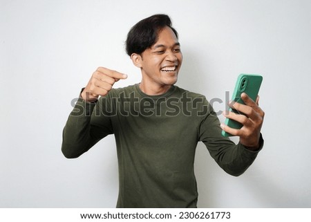Adult Asian man smiling face while read message and pointing in his mobile phone