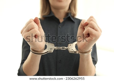 Female person with metal handcuffs in prison cell. Arrest of criminal for judgement in state court. Restoration of justice in state Royalty-Free Stock Photo #2306262955