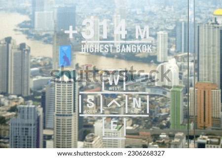 Label on glass mirror to display the height and the direction on a tower with background of Bangkok city