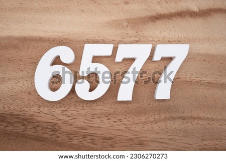 White number 6577 on a brown and light brown wooden background.