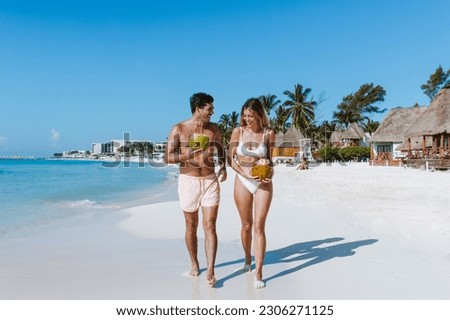 Hispanic young couple holding a coconut and having fun on caribbean beach in holidays or vacations in Mexico Latin America Royalty-Free Stock Photo #2306271125