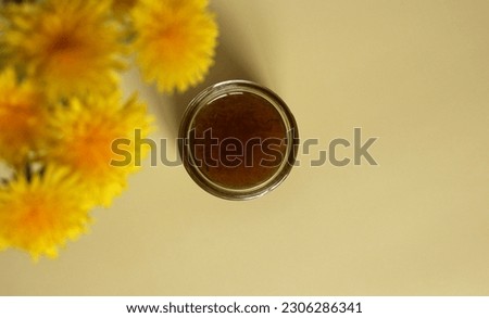 Dandelion flower jam in a glass jar on a beige background