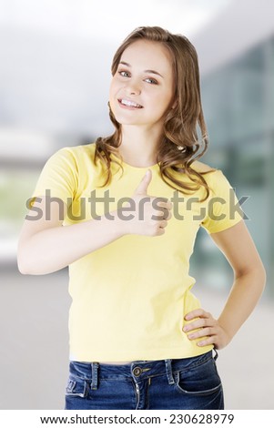 Beautiful teen woman in casual clothes gesturing thumbs up