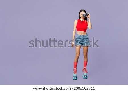 Full body cheerful young latin woman she wear red casual clothes rollers rollerblading taking photo on photocamera isolated on plain pastel purple background. Summer sport lifestyle leisure concept