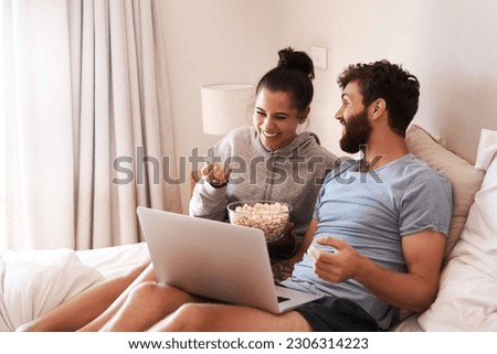 Laptop, watching movie and popcorn with laughing couple in bed for streaming, relax or internet. Subscription, happy or comic man and woman at home for social media, funny and free time on weekend