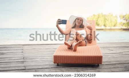 Young woman, lounge selfie and cocktail on holiday by the ocean on a deck chair with a smile. Female person, travel and Maldives island in summer taking a photo for a profile picture and social media Royalty-Free Stock Photo #2306314269