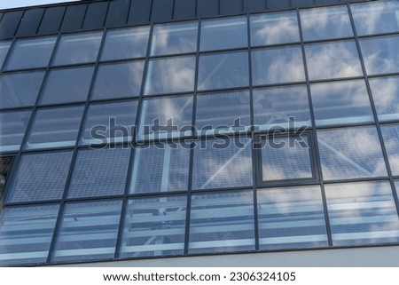 Bottom view of a modern skyscraper building with glass window against sky background for promotional content. Contemporary business centre with new perspective design.
