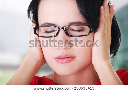 Closeup of frustrated young woman holding her ears
