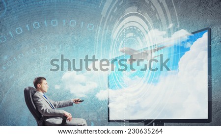 Young businessman sitting in chair behind tv with click in hand