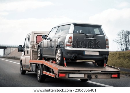 Tow truck with broken car on country road. Tow truck transporting car on the highway. Car service transportation concept. Royalty-Free Stock Photo #2306356401