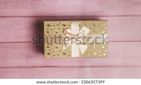 Gift box over pink wooden background, top view