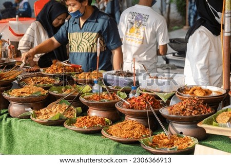Variety of Indonesian dish served on clay plate and banana leaf with Indonesian people background