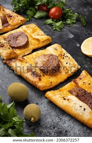 Sausage Pide or Sausage pizza Sucuklu Pide, on black dark stone table background