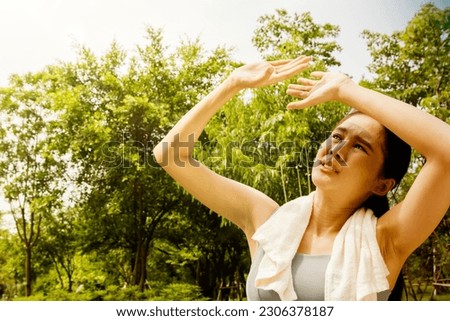 Asian woman doing sport jogging feeling sun and heat too hot during jogging in park sweltering summer weather covering face with hands covering face against UV rays : Sun protection health care concep Royalty-Free Stock Photo #2306378187
