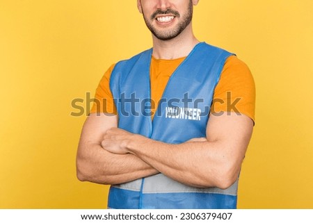 Unidentified young man with a warm smile, wearing a volunteer vest, symbolizing dedication and community service Royalty-Free Stock Photo #2306379407