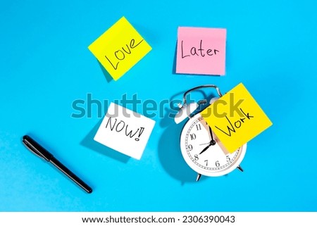Alarm clock and colorful paper reminders on a blue background, top view.