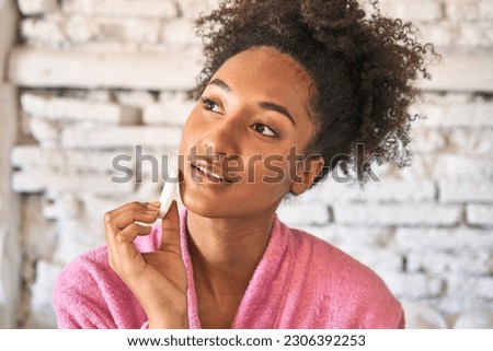 Radiant young woman, fresh from shower, holds makeup sponge, embracing the concept of beauty.