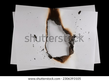 Burned, charred white paper scrap isolated on black background, top view