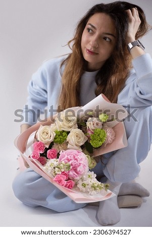 Woman with a delicate summer bouquet of flowers. The florist creates a red beautiful bouquet of mixed flowers. Flower shop. Fresh bouquet. Master classes and floristry courses. Flower delivery.