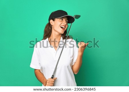 Young caucasian golfer holding a golf stick isolated Young caucasian golpoints with thumb finger away, laughing and carefree. Royalty-Free Stock Photo #2306396845